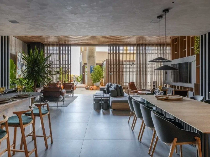 Sala e cozinha integradas com brises de madeira, mobiliario curado e paleta sofisticada projetadas por arquitetura de interiores