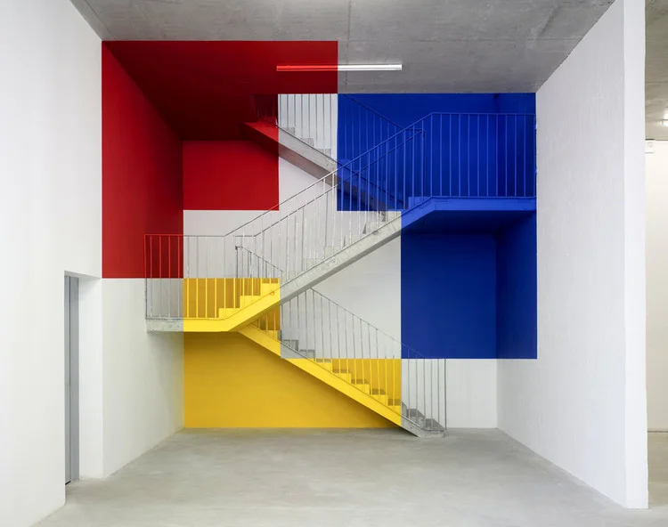 Escada de concreto pintada em vermelho, azul e amarelo no estilo Mondrian, exemplo de arquitetura de interiores e paisagismo cromático