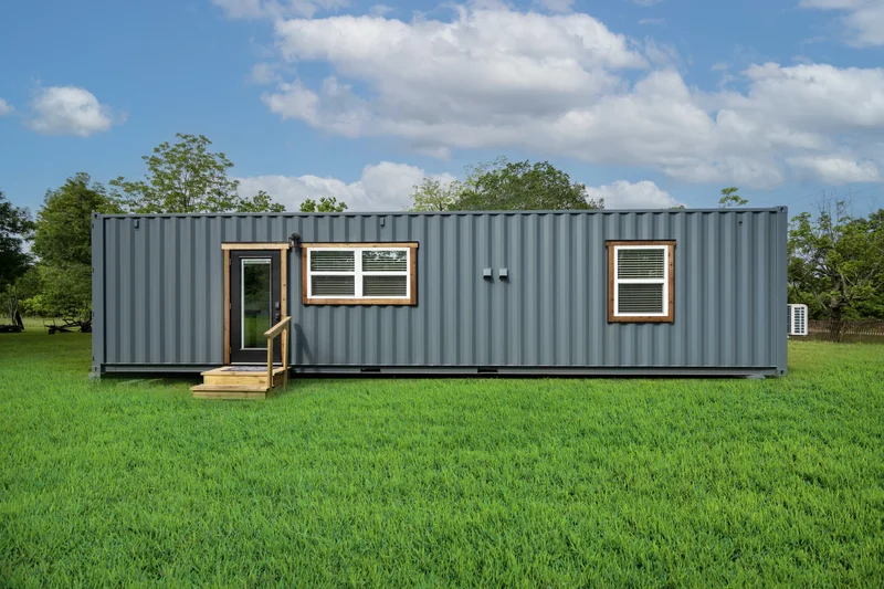 Pequena casa container de um módulo, com um grande deck de madeira na frente, ideal para um casal ou como casa de hóspedes.