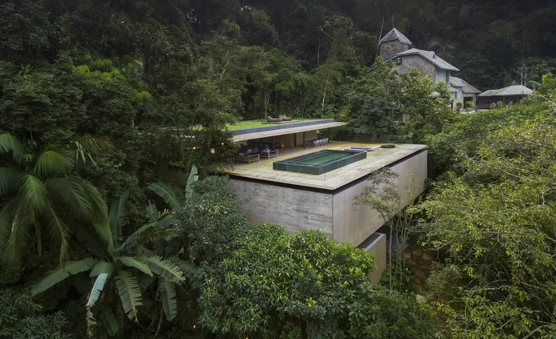Casa contemporânea em concreto aparente com cobertura verde implantada em encosta de mata atlântica densa em Petrópolis