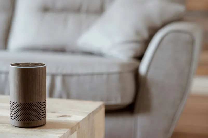 Smart speaker sobre mesa de madeira em sala minimalista — dispositivo de controle por voz integrado ao ambiente da casa inteligente