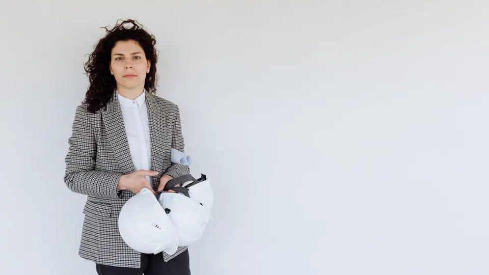 Arquiteta profissional com capacete e planta — posicionamento e carreira em arquitetura