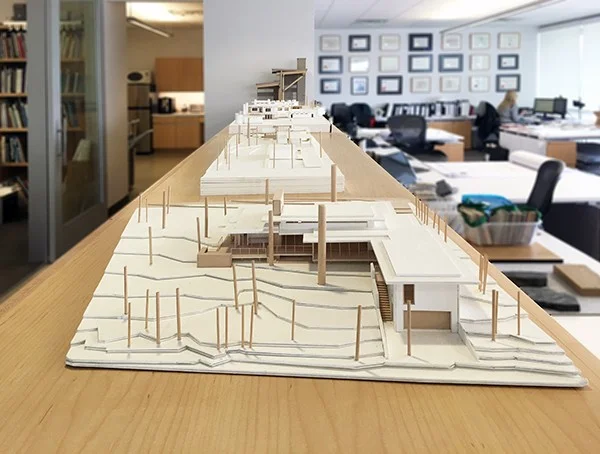 Maquetes urbanísticas em escala 1:500 expostas sobre bancada em escritório de arquitetura