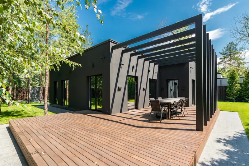 Deck de madeira em área de jardim com mesa e cadeiras, integrado à natureza