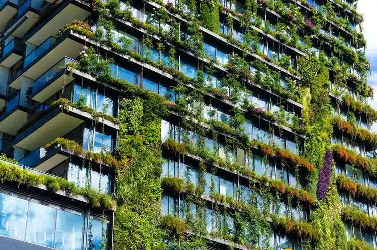 Fachada vegetal de torre residencial com plantas em sacadas escalonadas e cobertura verde