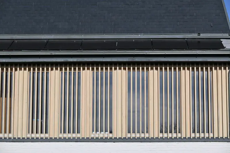 Detalhe de fachada com painéis de madeira ripada em projeto de arquitetura sustentável com sombreamento integrado