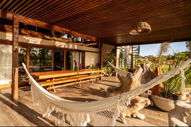 Varanda de madeira com rede e deck em Itaúnas, Espírito Santo — exemplo de integração entre espaço externo, brises e vegetação tropical brasileira