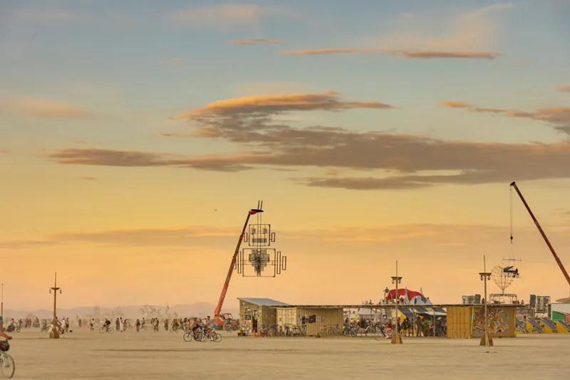 Instalação artística no festival Burning Man ao pôr do sol — estrutura efêmera de grande escala no deserto de Nevada