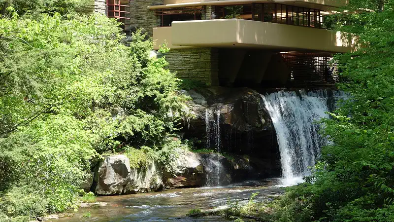 Vista frontal da Casa da Cascata mostrando os terraços de concreto em balanço sobre a queda d'água