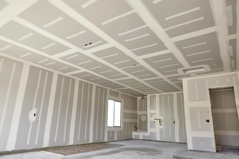 Interior de obra com paredes e forro em drywall já chapeados e juntas tratadas com massa branca aguardando pintura