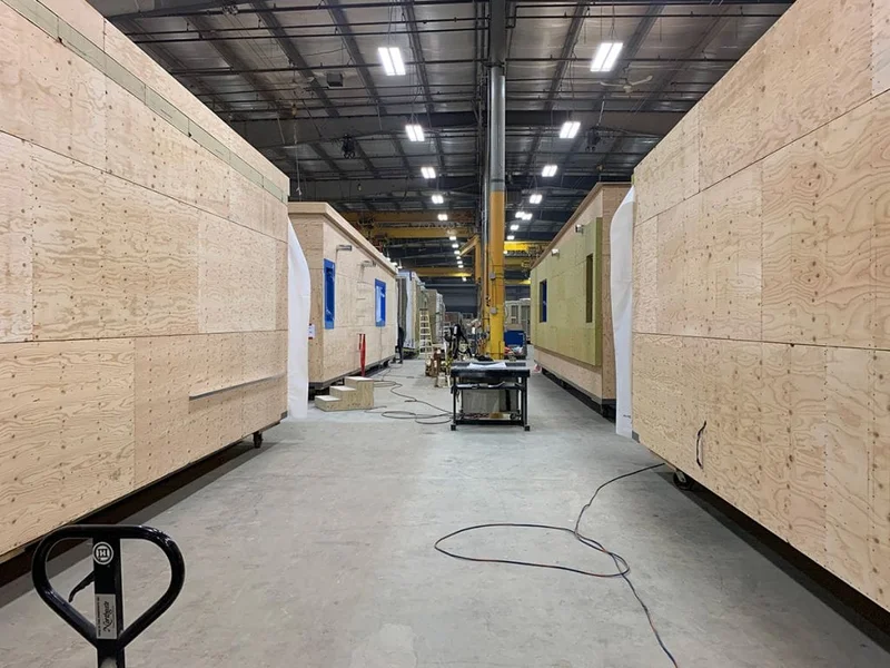 Operários montando um módulo de uma casa modular em canteiro de obras.