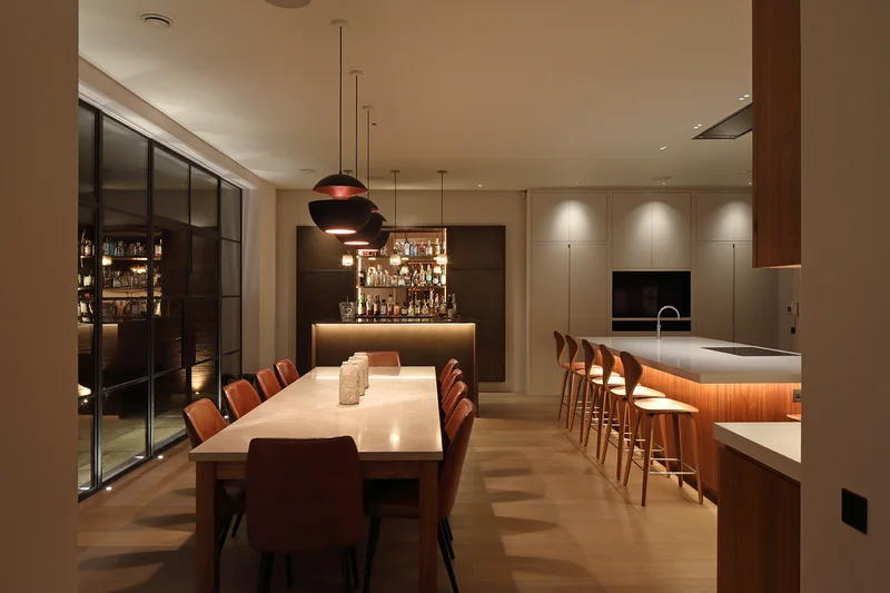 Cozinha americana com as 4 camadas de iluminação: geral, tarefa em bancada, acento em prateleiras e pendentes decorativos