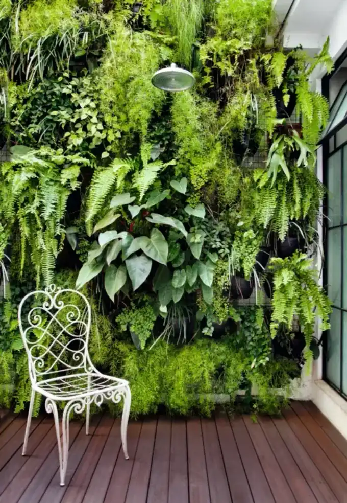 Jardim vertical residencial em varanda com cadeira de ferro, samambaias e plantas tropicais