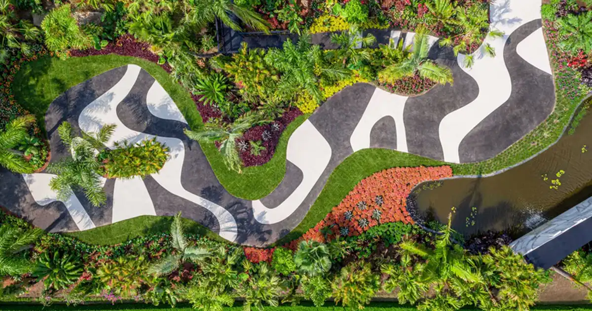 Vista aérea de jardim no estilo Burle Marx com calçada em curvas brancas e pretas e canteiros geométricos de plantas tropicais