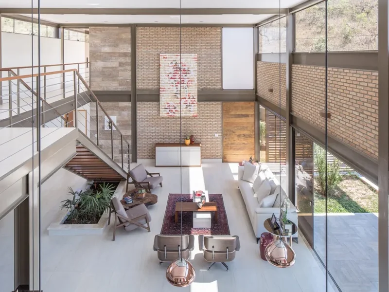 Sala duplex com pé-direito alto vista de cima mostrando escada e mezanino abertos para o ambiente