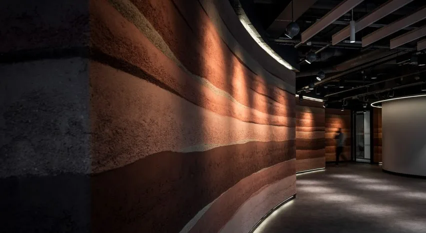 Parede curva com textura em camadas terracota num ambiente comercial premium