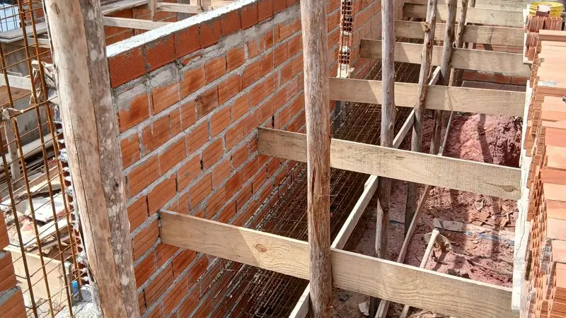 Forma de madeira escorada com armadura aparente para concretagem de viga sobre alvenaria de bloco ceramico em obra brasileira